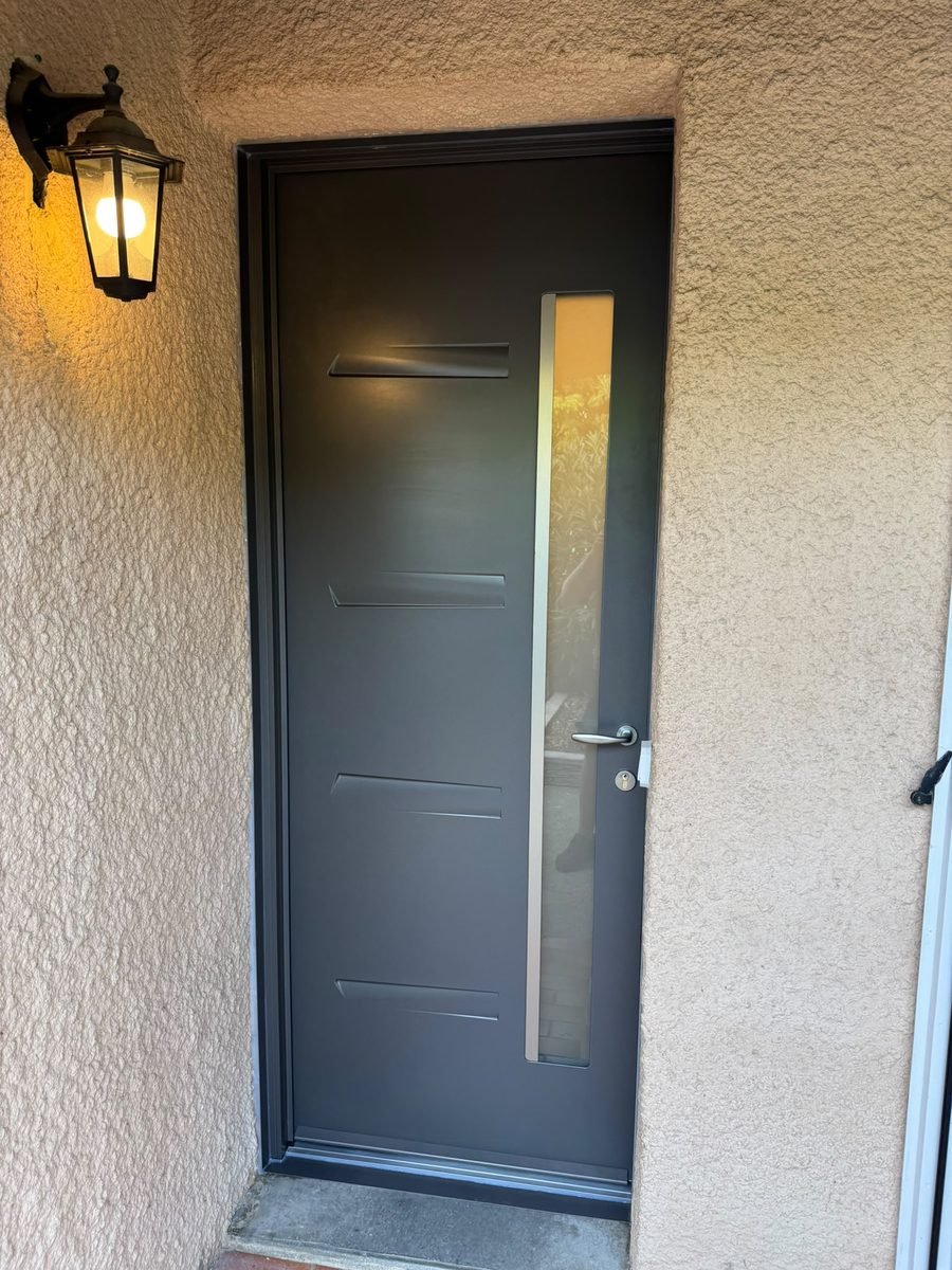 Nouvelle porte d'entrée en aluminium gris anthracite avec décors horizontaux et vitrage vertical