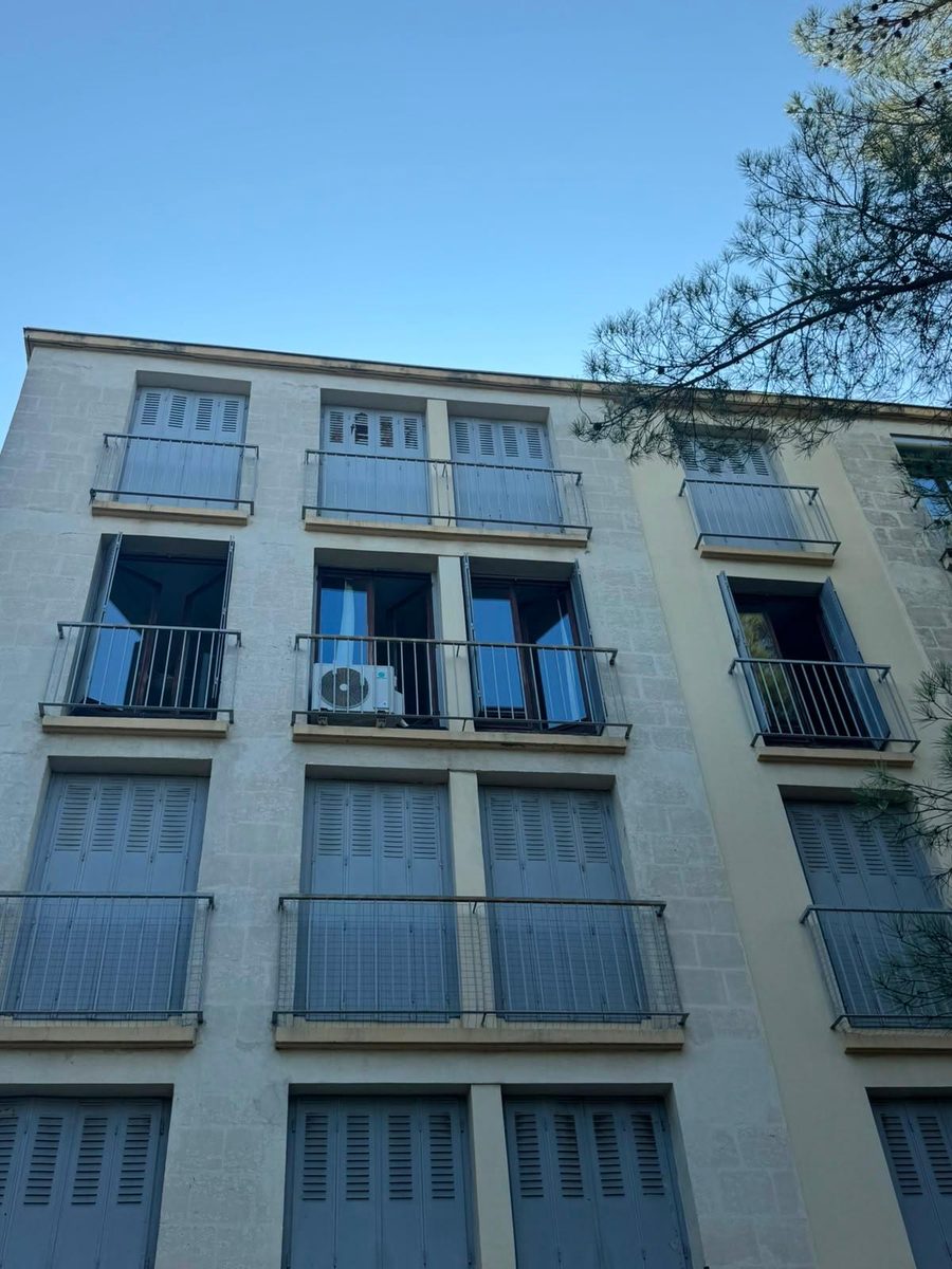 Façade d'immeuble avec fenêtres bois ouvertes et volets battants gris, avant la pose